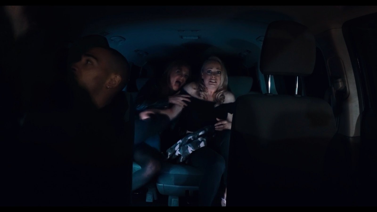 Two women scream in the back of a darkened car as a stranger watches in the foreground, Fear Hunters
