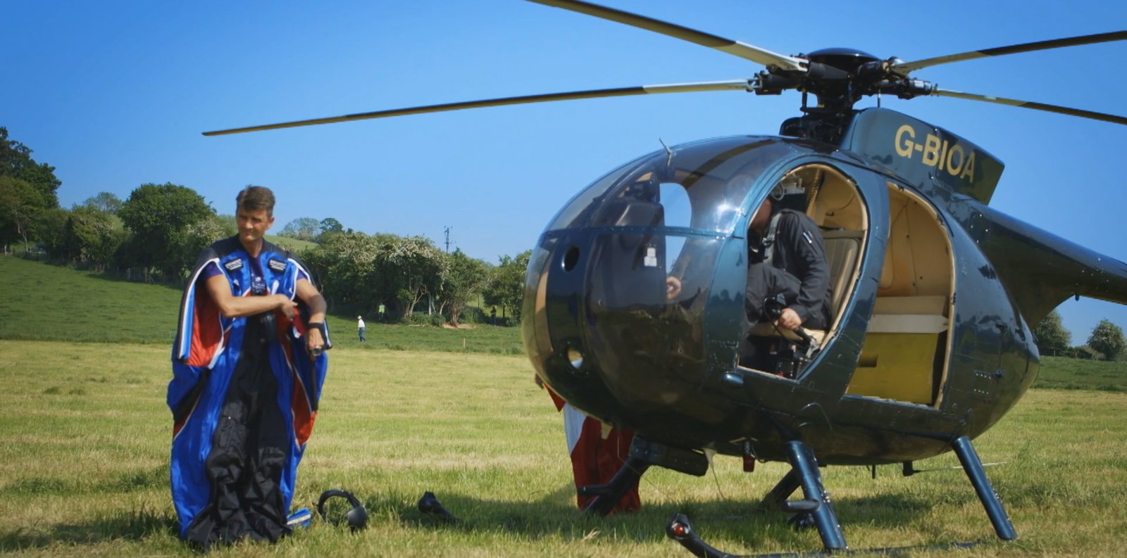 Gary Connery in his Union Jack wingsuit beside the helicopter before the jump, a graded frame from The Man Who Flew to Earth